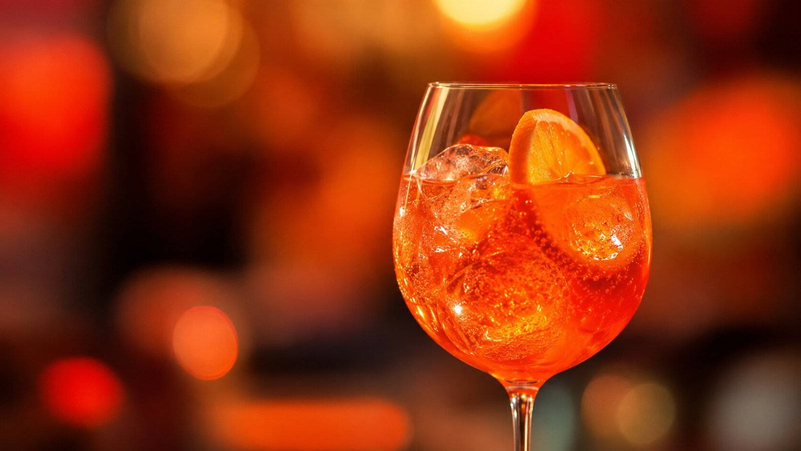 Aperol Spritz vor stark verschwommenem orangefarbenem Neonlicht
