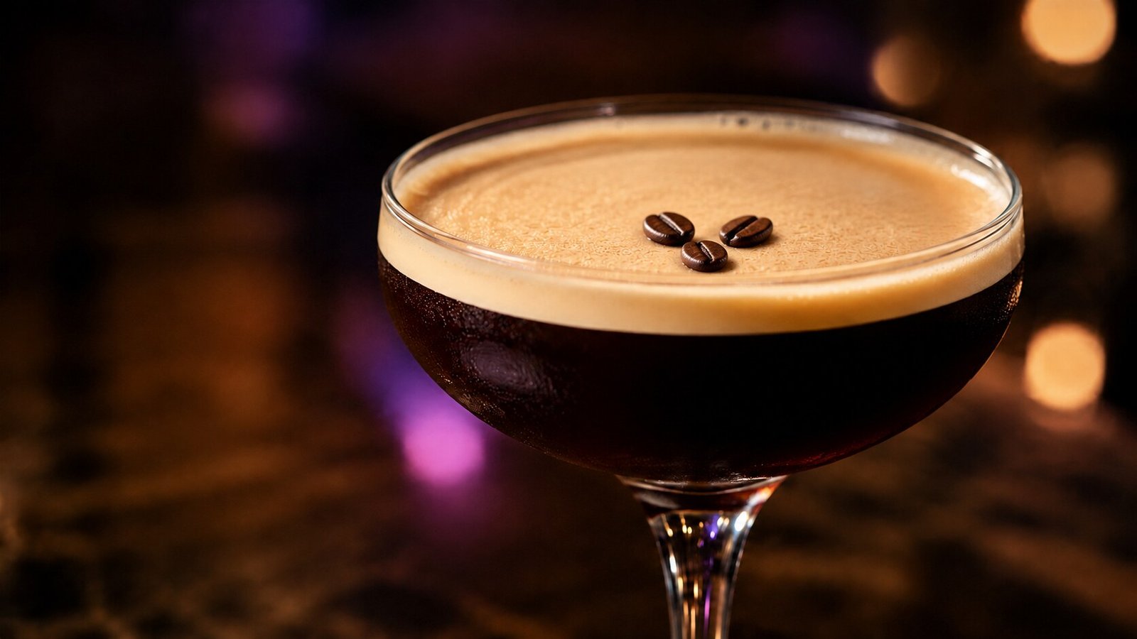 Espresso Martini mit drei Kaffeebohnen vor stark verschwommenem kaffeebraunem Licht