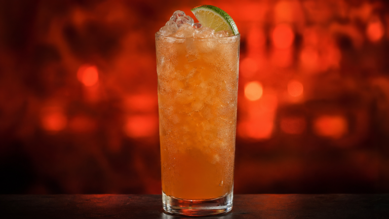 Planter’s Punch vor extrem unscharfem Neonhintergrund in der Farbe des Drinks