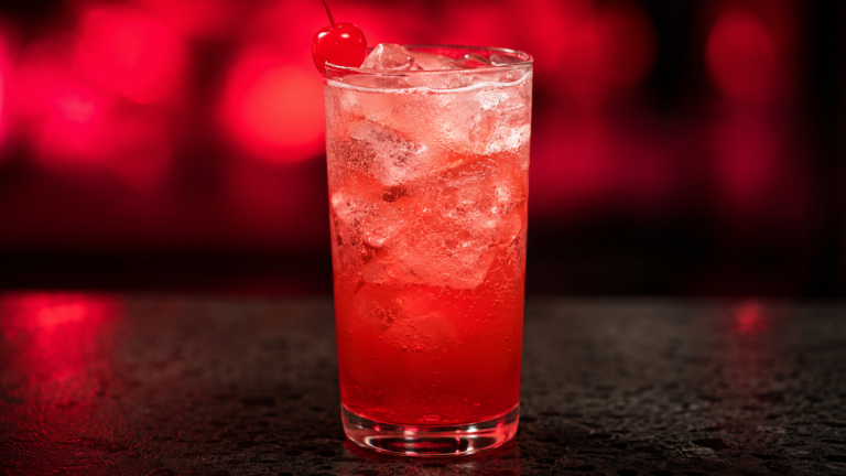 Shirley Temple vor extrem unscharfem Neonhintergrund in der Farbe des Drinks